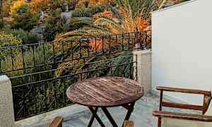 Udsigt fra en terrasse med bord og stole samt en borg på en bakke i baggrunden. (AI-genereret tekst)