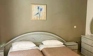 To enkeltsenge med brune sengetæpper, et maleri på væggen ovenover og en kommode til højre. (AI-genereret tekst)