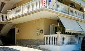 Bygning med altaner og markiser ved en stenlagt indgang. (AI-genereret tekst)