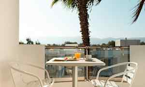 En altan med et bord, to hvide stole og morgenmad serveret. En palme ses i baggrunden. (AI-genereret tekst)