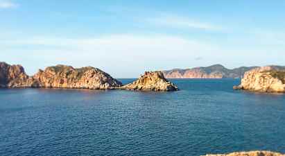 Kystlandskab med klippeøer i havet under en klar blå himmel. (AI-genereret tekst)