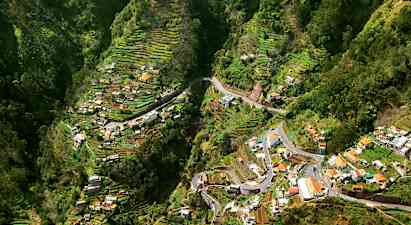 Udsigt over en dal med terrasserede landbrugsområder og huse. (AI-genereret tekst)