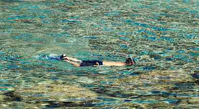 Person med snorkel svømmer i klart vand. (AI-genereret tekst)