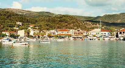 En havbugt med småbåde og en kystby fyldt med huse og træer i baggrunden. (AI-genereret tekst)