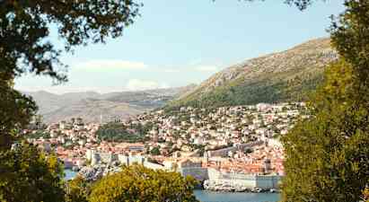 En udsigt over Dubrovnik med dens historiske bymur, omgivet af grønne områder. (AI-genereret tekst)
