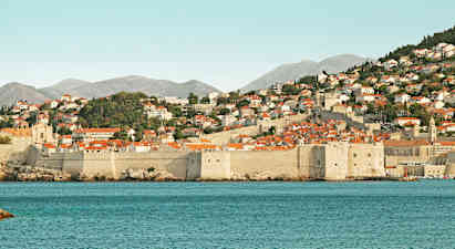 Stenbyers mure og røde tage ved kysten. (AI-genereret tekst)