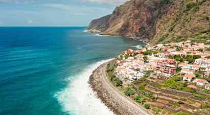 Udsigt over en kystlinje med en landsby på klippen og havet i baggrunden. (AI-genereret tekst)