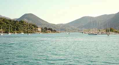 En udsigt over en bugt med sejlbåde og omkringliggende grønne bakker. (AI-genereret tekst)