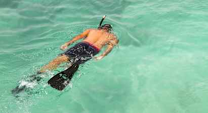 En person snorkler i klart turkisblåt vand. (AI-genereret tekst)