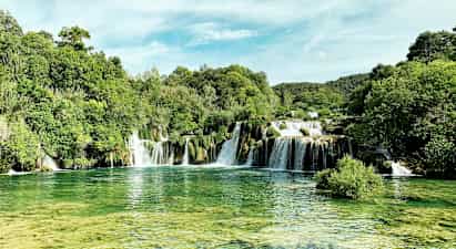 Et naturskønt vandfald omgivet af frodig vegetation. (AI-genereret tekst)