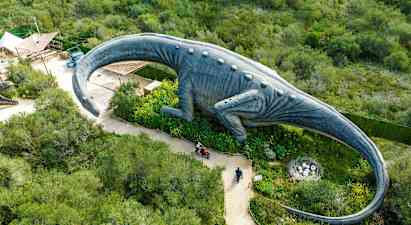 En stor dinosaurstatue omgivet af grønt set oppefra. (AI-genereret tekst)