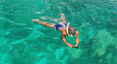 En person svømmer i klart vand med snorkeludstyr. (AI-genereret tekst)