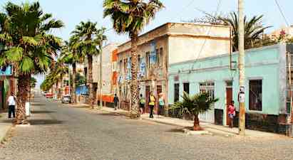 Gade med palmer og farverige bygninger. (AI-genereret tekst)