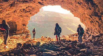 En gruppe mennesker udforsker en hule med udsigt over et bjerglandskab. (AI-genereret tekst)