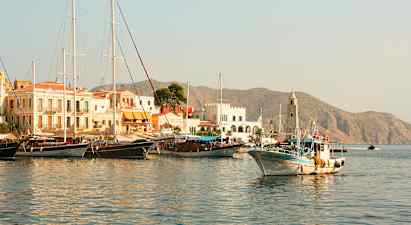 En havn med både og bygninger, bjerge ses i baggrunden. (AI-genereret tekst)