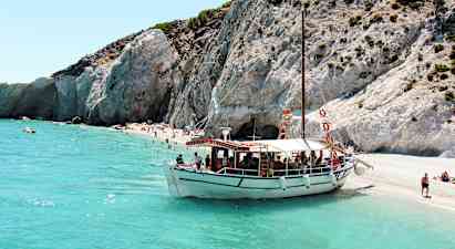 En båd ligger fortøjet ved en strand med klipper og klart turkisblåt vand. (AI-genereret tekst)