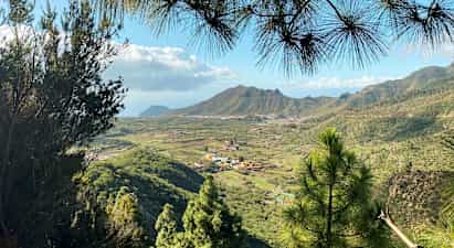 Udsigt over et grønt dalområde med landsbyer og bjerge i baggrunden. (AI-genereret tekst)