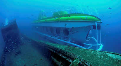 Undervandsudsigt af en ubåd ved siden af et gammelt skibsvrag omgivet af fisk. (AI-genereret tekst)