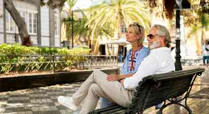 Personer sidder på en parkbænk i en bymiljø. (AI-genereret tekst)