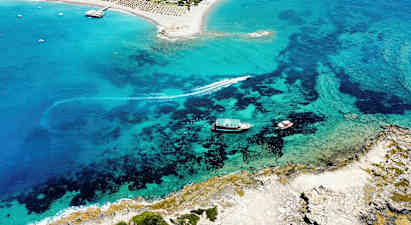 Luftfoto af en sandstrand ved et turistområde med klart blåt vand. (AI-genereret tekst)