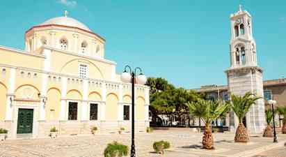 En gul bygning med kuppel og et klokketårn samt palmer og gadelys. (AI-genereret tekst)