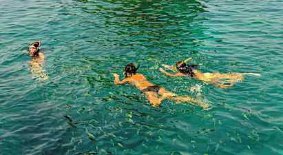 Personer der snorkler i klart vand med fisk omkring. (AI-genereret tekst)