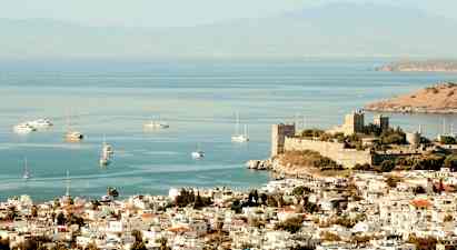 Billede af en by ved havet med en gammel borg nær kysten og både på vandet. (AI-genereret tekst)