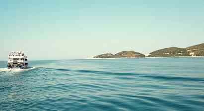 En båd sejler over et stille hav med nogle lave øer i horisonten. (AI-genereret tekst)