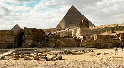 Stenet område med pyramider og sfinks under en klar himmel. (AI-genereret tekst)