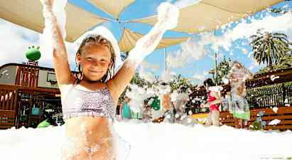 En gruppe mennesker nyder en aktivitet med skum under et skærmtag udendørs. (AI-genereret tekst)