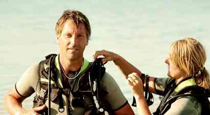 To personer i dykkerudstyr står i lavt vand. (AI-genereret tekst)