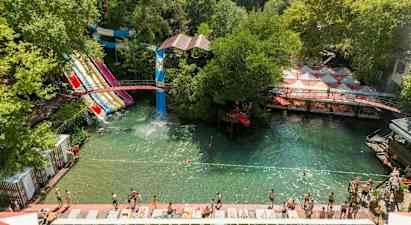 Vandpark med flere vandrutsjebaner og badeområde omgivet af grønne områder. (AI-genereret tekst)