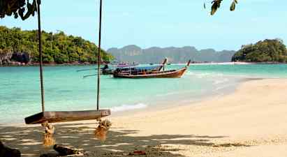 Strand med gynge og en træbåd på vandet foran skovklædte øer. (AI-genereret tekst)