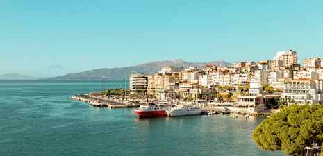 Udsigt over en by ved havet med småbådshavn og bygninger langs kysten. (AI-genereret tekst)