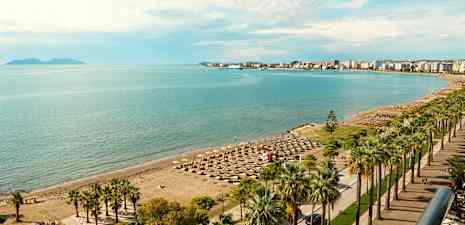 Strand med parasoller og havet i baggrunden. (AI-genereret tekst)