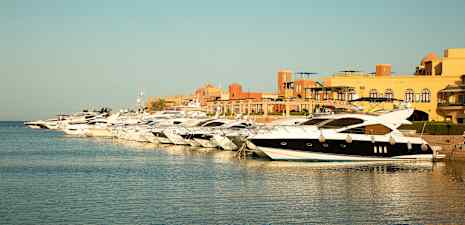 Flere motorbåde ligger fortøjet ved kajen i en havn. (AI-genereret tekst)