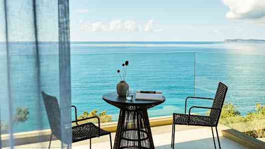 Altan med havudsigt, bord med vase og to stole. (AI-genereret tekst)