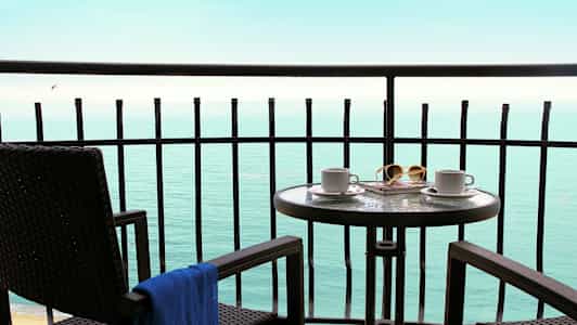 Altan med bord og stole med udsigt til havet. (AI-genereret tekst)