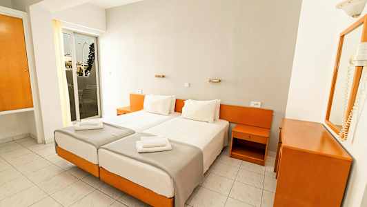 To enkeltsenge med hvide sengelinned i et hotelværelse med hvidt og træinteriør. (AI-genereret tekst)