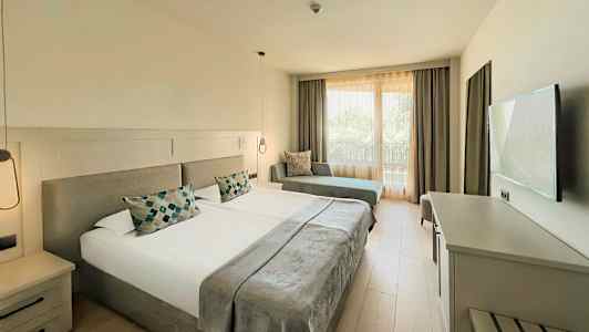 Et hotelværelse med to enkeltsenge, en sofa og et TV. (AI-genereret tekst)