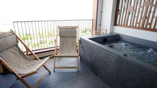 Terrasse med to liggestole og et boblebad. (AI-genereret tekst)