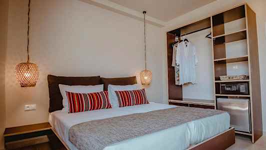 Soveværelse med dobbeltseng, røde dekorative puder og åben garderobe. (AI-genereret tekst)