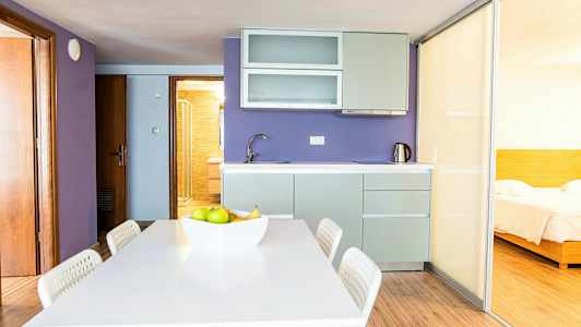 Et køkken med lilla vægge, en spiseplads og en skydedør, der fører til et soveværelse. (AI-genereret tekst)