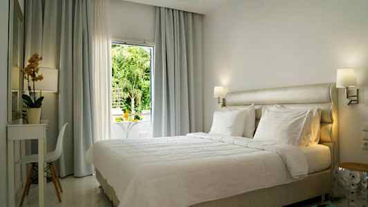 Lyst og moderne indrettet hotelværelse med en stor seng og vindue med udsigt. (AI-genereret tekst)