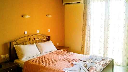 Et soveværelse med en dobbeltseng, orange sengetøj og to håndklæder dekoreret på sengen. (AI-genereret tekst)