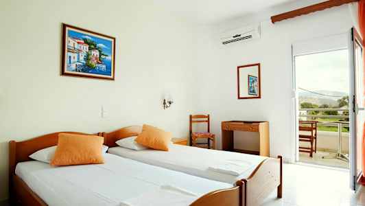 Hotelværelse med to enkeltsenge, et skrivebord med stol og balkon med udsigt. (AI-genereret tekst)