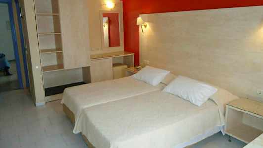 Et hotelværelse med to enkeltsenge ved siden af hinanden, et skab og et bord med spejl. (AI-genereret tekst)