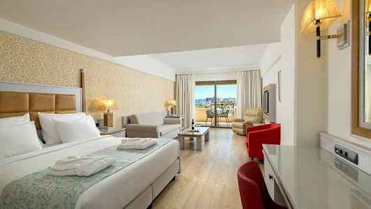 Et hotelværelse med en seng, siddeområde og en balkon med udsigt. (AI-genereret tekst)