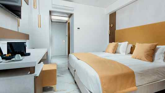 Et moderne hotelværelse med en stor seng, marmorgulv og en arbejdsplads med kaffemaskine. (AI-genereret tekst)