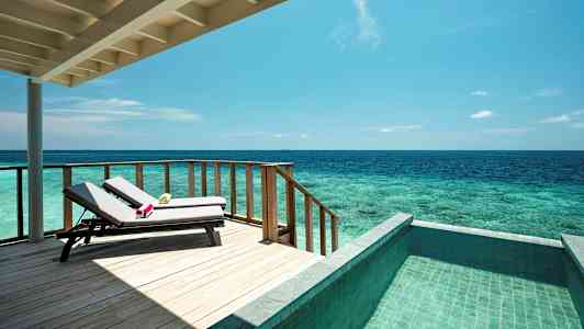 En terrasse med liggestole, havudsigt og en pool. (AI-genereret tekst)